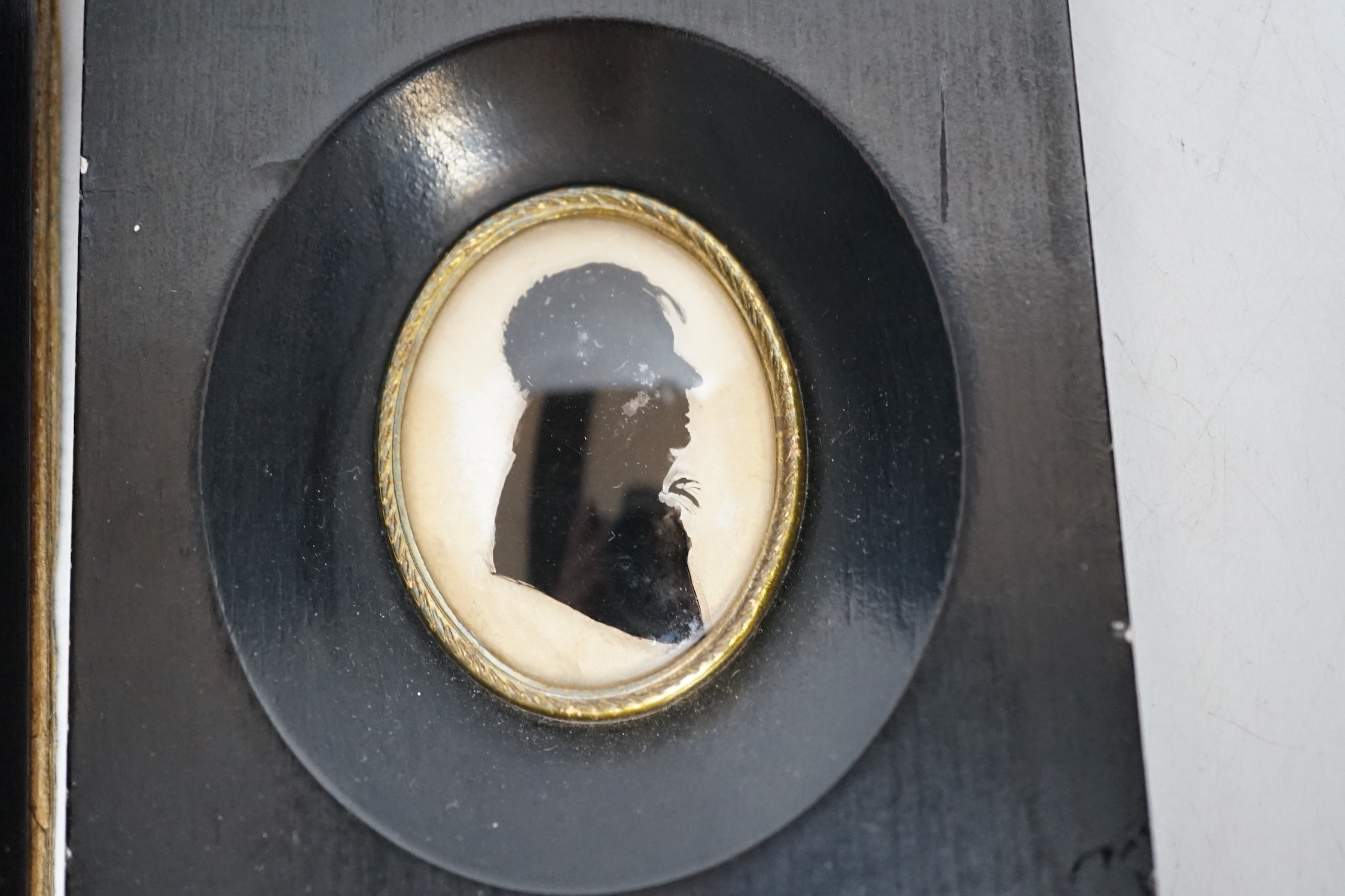 Three miniature reverse glass painted silhouettes, a relief plaque of the virgin and child and a watercolour portrait pendant